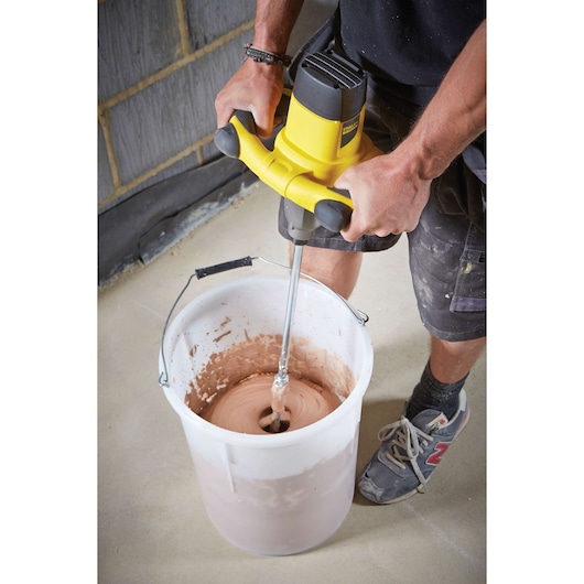 STANLEY FME190-QS mixer being used to blend material in a large white bucket on a construction site.