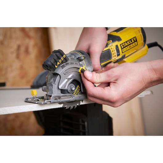 Photo of STANLEY FME380K circular saw in use, close-up on person's hands guiding saw on wood board.