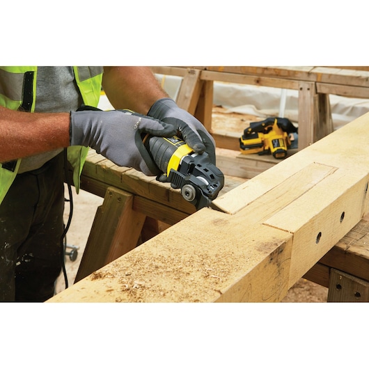 STANLEY FME650K multi-tool used to cut wood on workbench in workshop, close-up of tool in action.