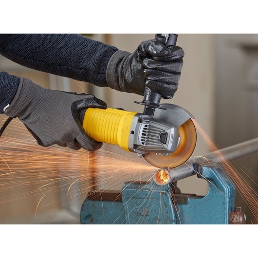 STANLEY FMEG220K angle grinder in use, cutting metal pipe and producing sparks, close-up view.