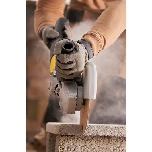 STANLEY FMEG232 angle grinder in use, cutting stone block, close-up photography.