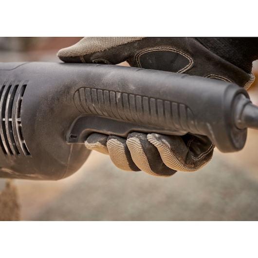 STANLEY FMEG232 angle grinder handle close-up held by a gloved hand outdoors.
