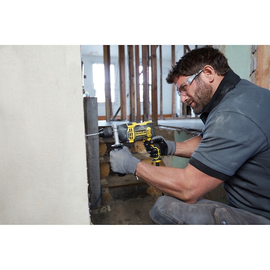 Photo of STANLEY FMEH750 hammer drill in use on a wall during construction renovation.