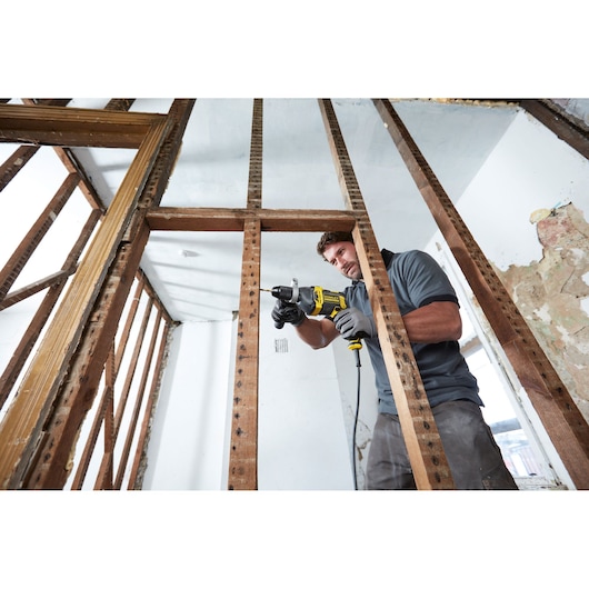 STANLEY FMEH750 corded drill used by a worker in a construction site, horizontal angle.