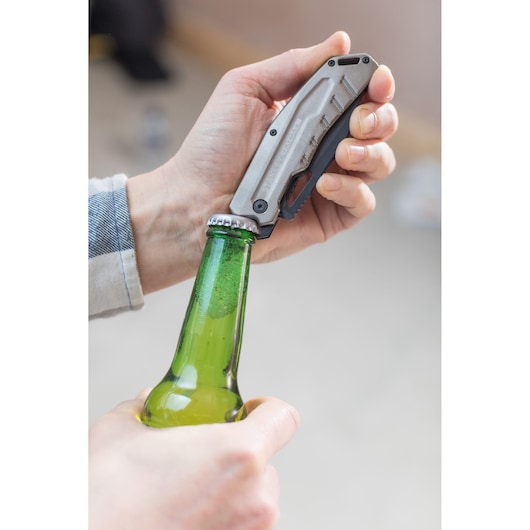 Photo of STANLEY FMHT0-10312 folding utility knife used to open a green glass bottle.
