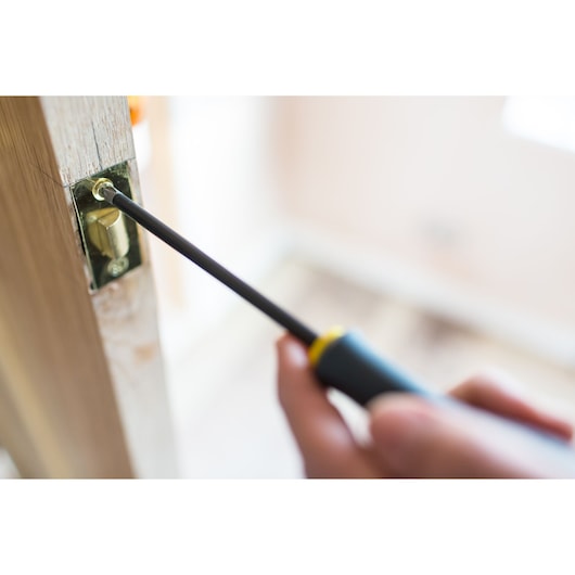 STANLEY FMHT0-62062 screwdriver in use tightening a brass door latch screw, close-up focus on tool and latch.