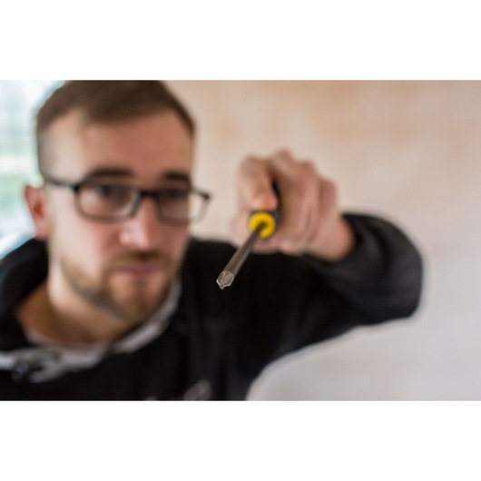 STANLEY FMHT0-62062 screwdriver with yellow and black handle held forward in close-up photography.