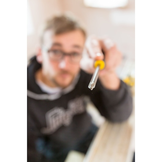 STANLEY FMHT0-62062 screwdriver with yellow-black handle held in hand, close-up focus on tip.