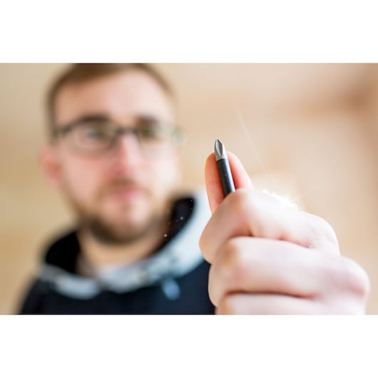 STANLEY FMHT0-62062 screwdriver bit held in hand, close-up photography, blurred background.