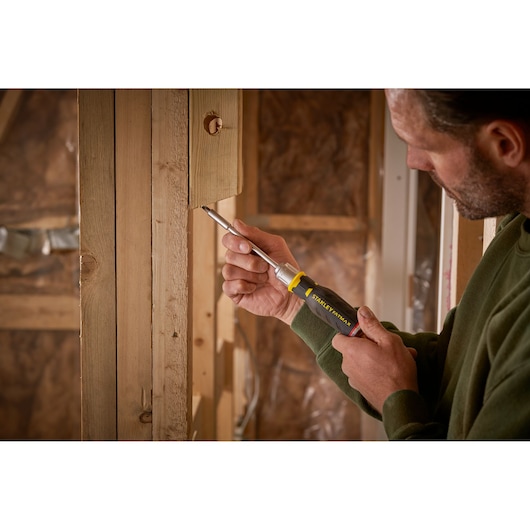 Photo of STANLEY FMHT0-62690 screwdriver used on wooden construction by person in green sweater.