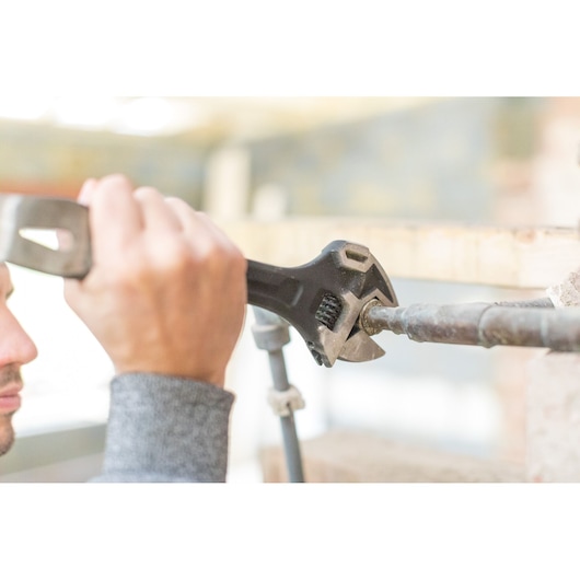 STANLEY FMHT0-75081 adjustable wrench used on a metal pipe, close-up photography.