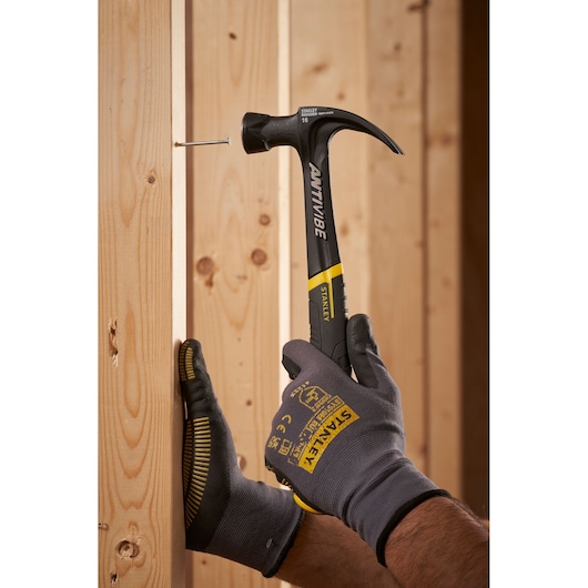 Photo of STANLEY FMHT1-51275 claw hammer with black and yellow handle driving nail into wooden beam.