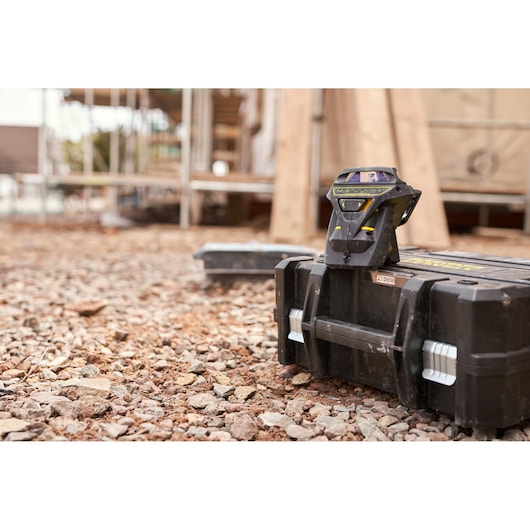STANLEY FMHT1-77356 laser level on black toolbox, outdoor construction site, angled front view.
