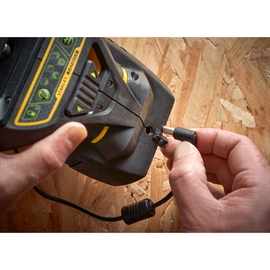 STANLEY FMHT1-77356 photography showing hands plugging power cable into black and yellow device on wood surface.