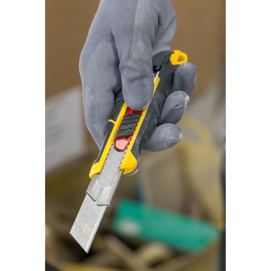 Photo of STANLEY FMHT10338-0 utility knife with yellow and black handle held in a gloved hand.