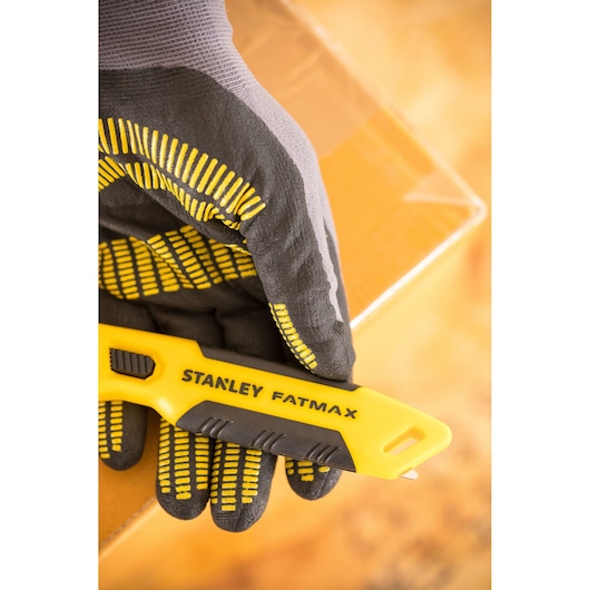 Photo of STANLEY FMHT10373-0 utility knife held by gloved hand, with cardboard box in background.