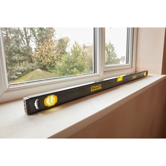STANLEY FMHT42447-1 black spirit level placed on windowsill, yellow vials, photography angled indoors.