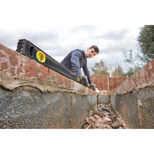 STANLEY FMHT42562-1 spirit level in use on brick wall, construction setting, angled view