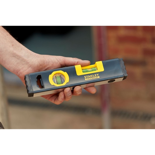 Photo of STANLEY FMHT42884-1 spirit level with yellow accents, held in hand, product in use.