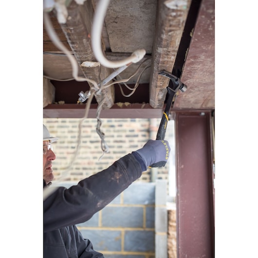 Photo of STANLEY FMHT51367-2 hammer in use for demolition under a ceiling, visible gloved hand holding the tool.