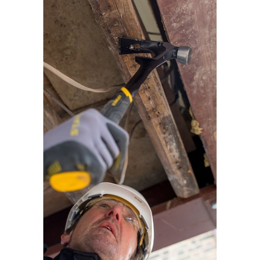 STANLEY FMHT51367-2 hammer used in construction, close-up angle showing striking head and black handle.
