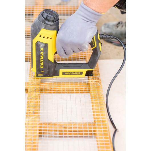 Photo of STANLEY FATMAX FMHT6-75934 electric multi-tacker stapling wire mesh to wood, close-up in use.