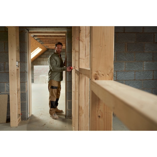 Photo of STANLEY FMHT77165-0 laser distance measurer used by worker in unfinished building.