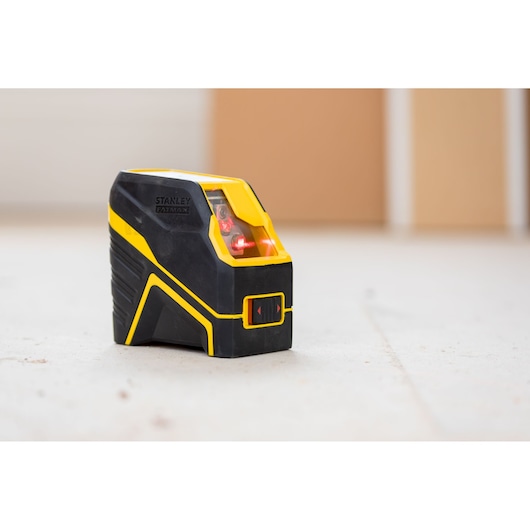 STANLEY FMHT77585-1 laser level, black and yellow, angled photography on light surface.