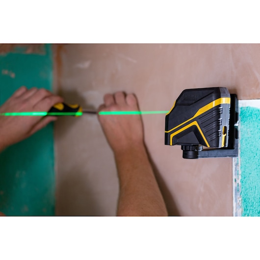STANLEY FMHT77586-1 laser level projects green line during wall installation task.