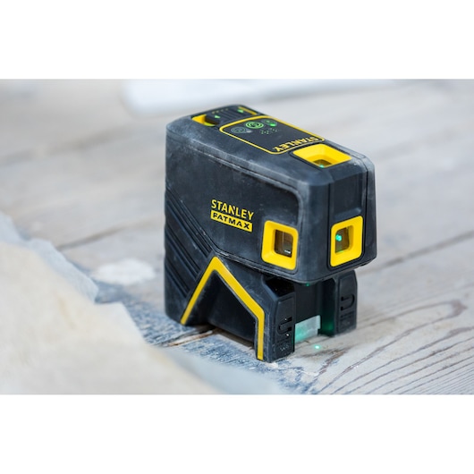 STANLEY FMHT77596-1 laser level, black and yellow, placed on wooden surface, product side view.