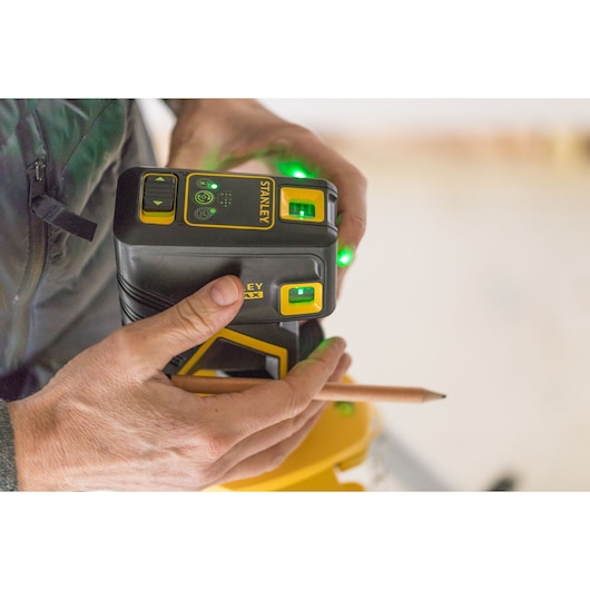 Photo of STANLEY FMHT77596-1 laser level device with green lights held by a person during use.