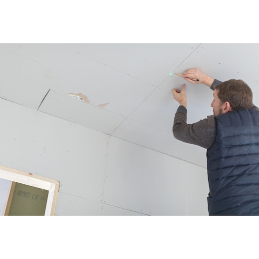 STANLEY FMHT77596-1 photography of person marking ceiling with pencil using green laser guide.