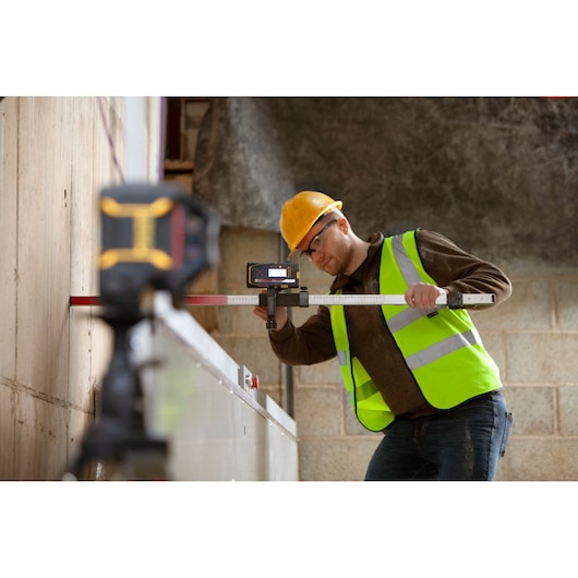 STANLEY FMHT77652-0 laser level in use on construction site by worker wearing high-visibility vest.