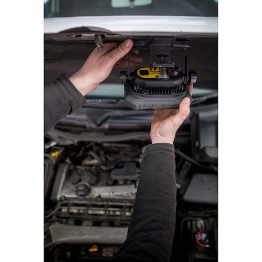 STANLEY FMHT81507-1 work light mounted under car hood, hands adjusting light, automotive repair context.