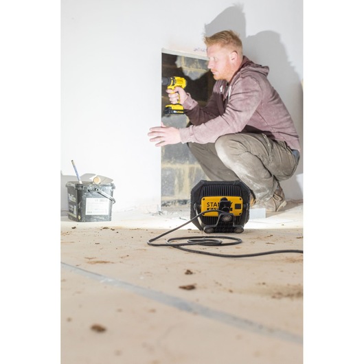 Photo of STANLEY FMHT81508-1 work light illuminating a construction site, with a worker using a power drill.
