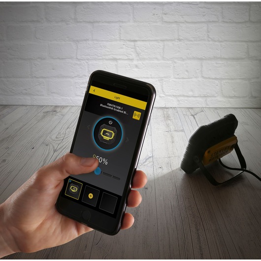 STANLEY FMHT81508-1 work light controlled via a smartphone app, hand adjusting the light settings.