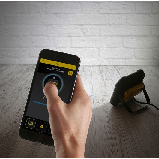 Photo of STANLEY FMHT81508-1 Bluetooth-enabled work light controlled by a smartphone app on a wood floor.