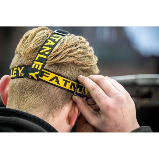 Photo of STANLEY FMHT81509-0 headlamp with yellow and black adjustable strap shown worn from rear view.