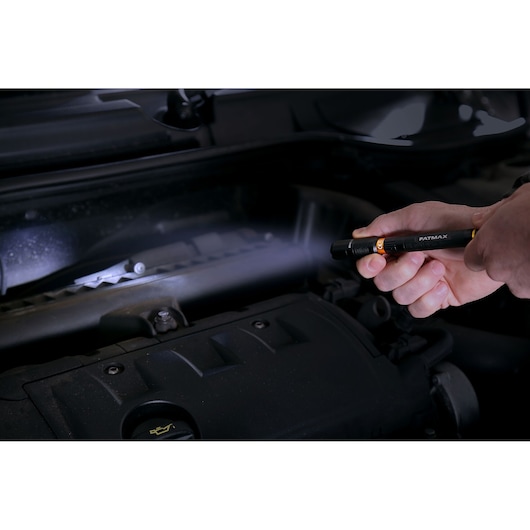 STANLEY FMHT81510-0 pen light flashlight used to inspect car engine in dark setting.