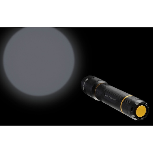 STANLEY FMHT81511-0 flashlight illuminating a wide beam, black and yellow design, angled on black background.