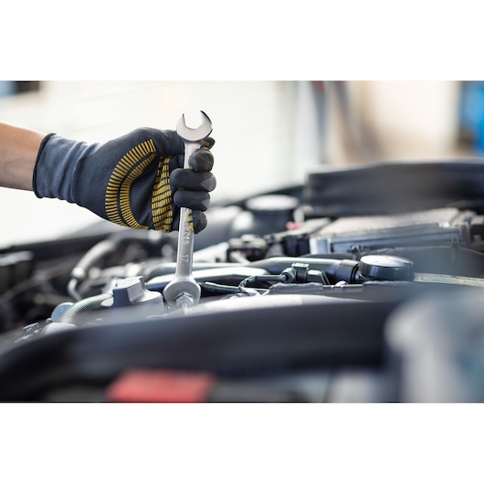 Photography of STANLEY FMMT13073-0 wrench in gloved hand working on car engine.