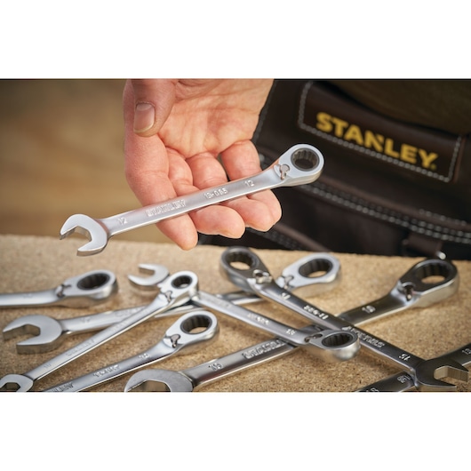 Photo of STANLEY FMMT13096-0 ratcheting wrench set, hand holding one wrench, wrenches on a work surface.