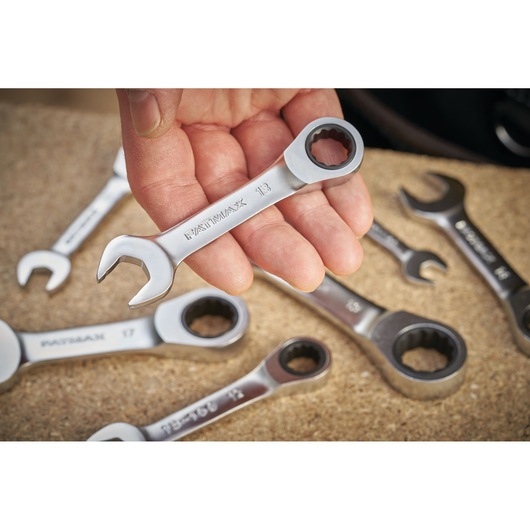 STANLEY FMMT13097-0 ratcheting combination wrench held in hand, with other wrenches on a work surface.