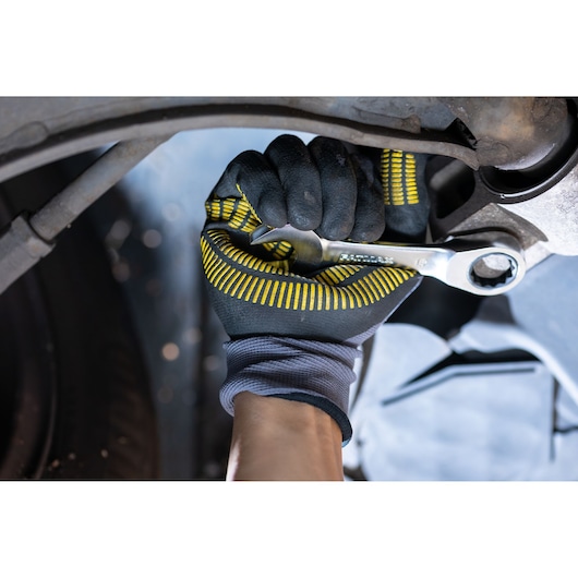STANLEY FMMT13098-0 wrench in use, mechanic wearing black and yellow gloves tightening a bolt under a vehicle.