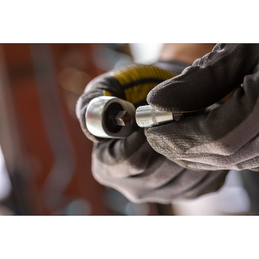 Photo of STANLEY FMMT17196-0 socket wrench in gloved hand, close-up view, silver finish.