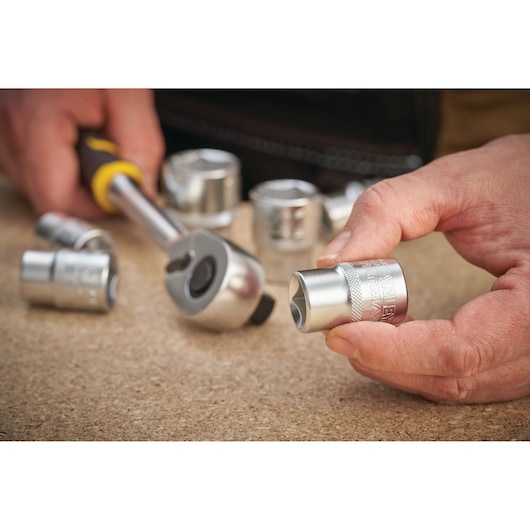STANLEY FMMT17238-0 chrome socket set and ratchet, close-up photo, tools held in hand.