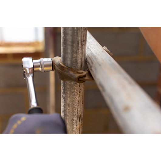 STANLEY FMMT17241-0 ratchet tightening a rusty clamp on metal scaffolding, close-up photography.