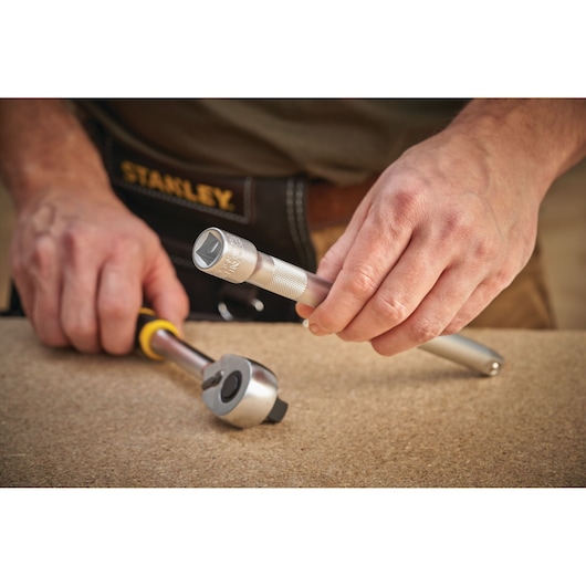 Stanley FMMT25122-0 ratchet and socket tool held by person, close-up on work surface.