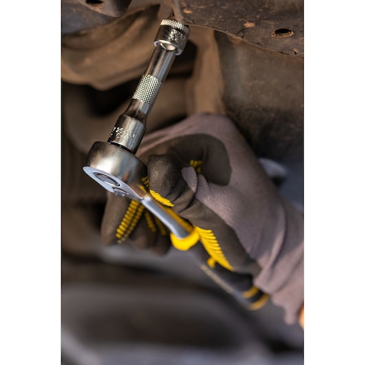 Stanley FMMT25122-0 ratchet tool in use, close-up, showing yellow and black handle grip.
