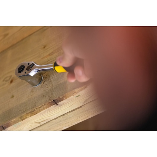 STANLEY FMMT82679-0 ratchet wrench with yellow handle in use on wooden surface.